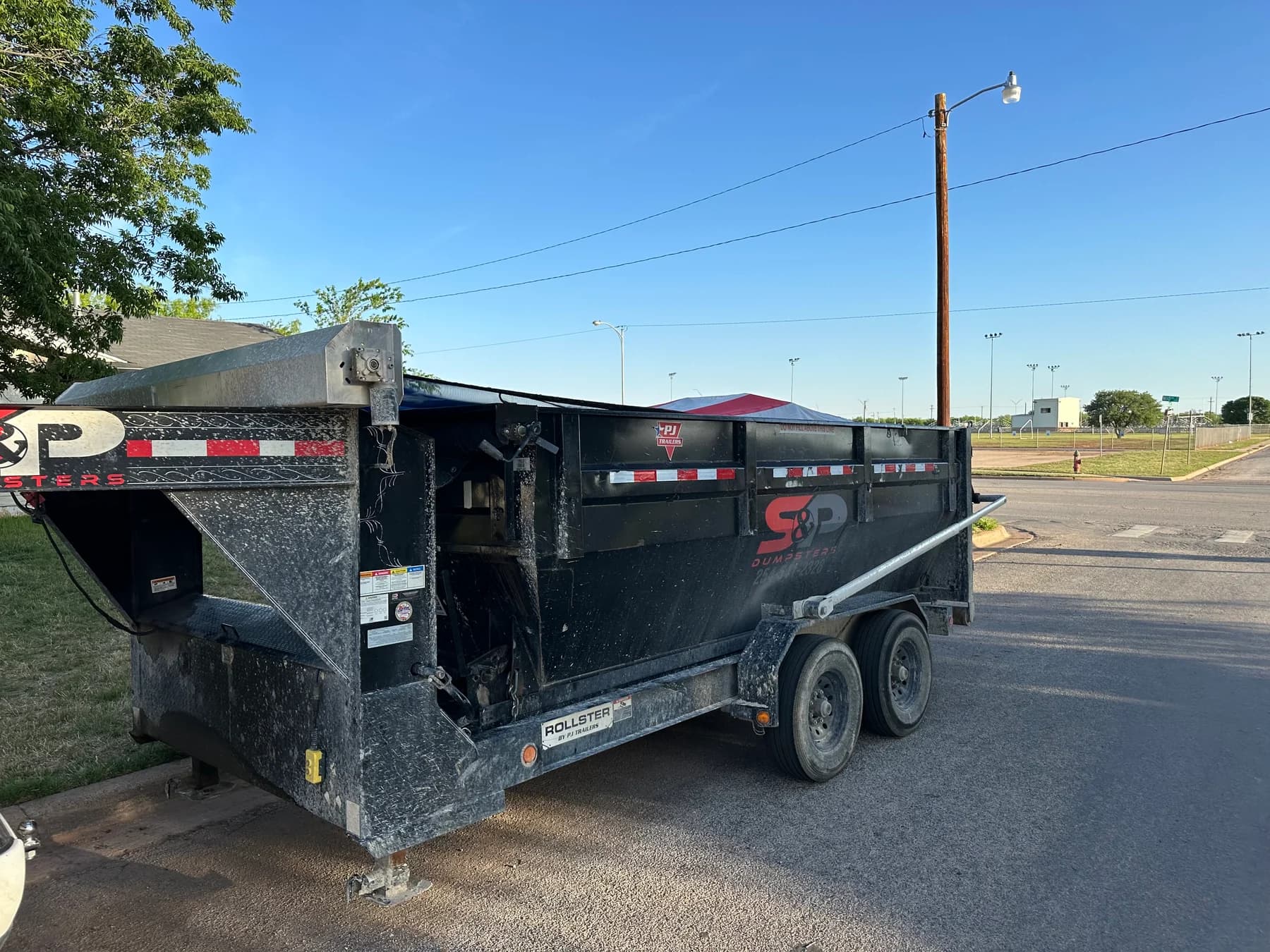 Black dumpster equipment on a trailer at the street