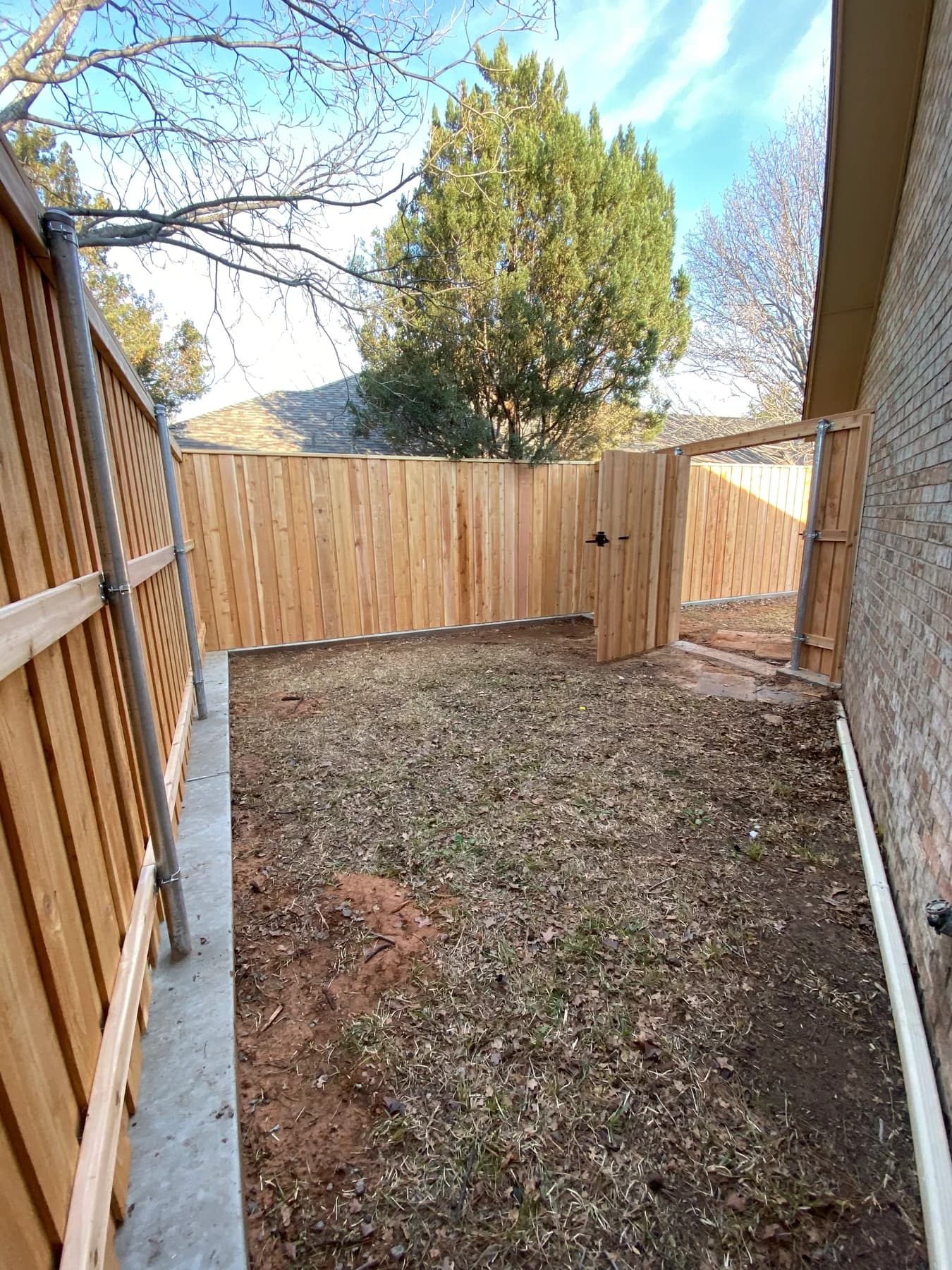 Concrete at the base of a Fortress Fencing wood fence