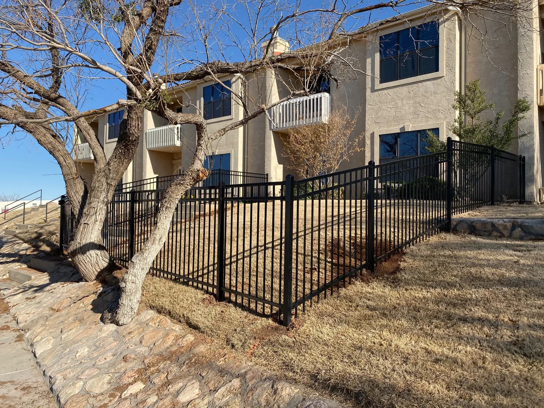 Black ornamental metal fence and gate beside a home